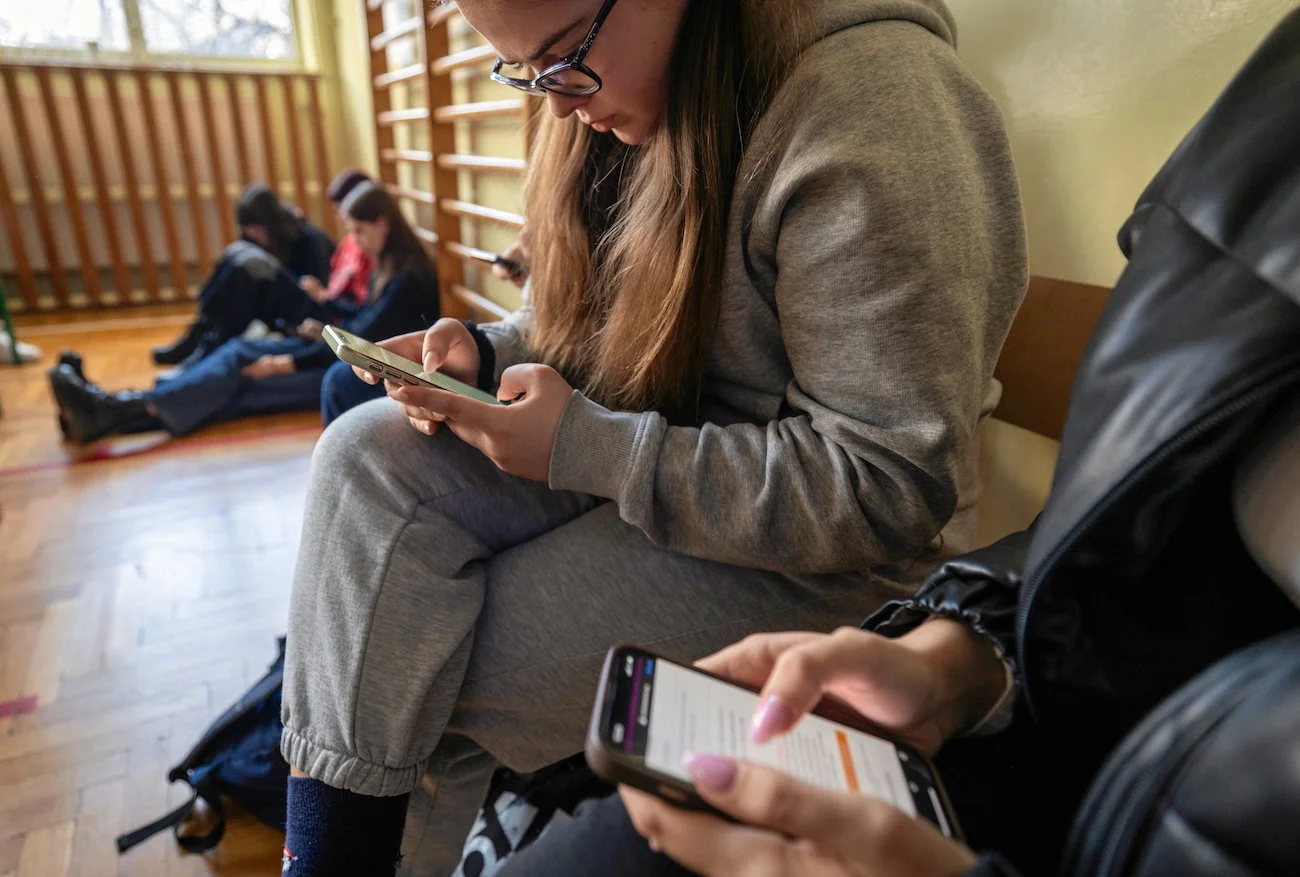 uczniowie liceum spędzają przerwę między lekcjami na przeglądaniu telefonów