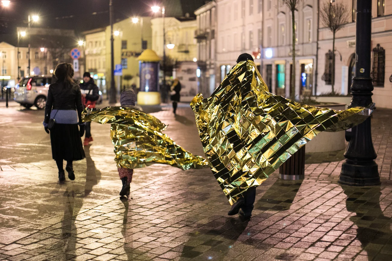 ludzie spacerujący w kocach termicznych