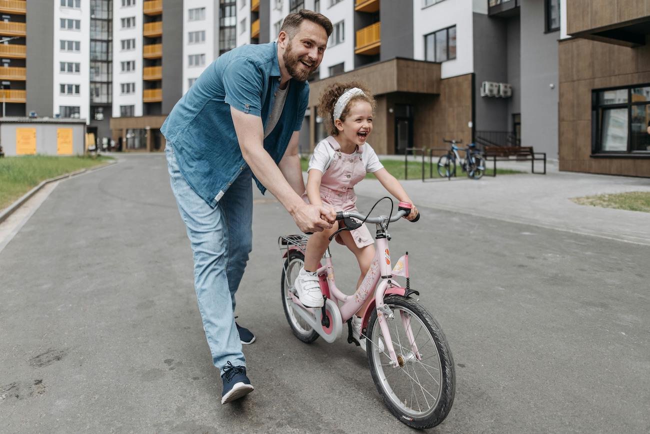 tata uczy córkę  jazdy na rowerze