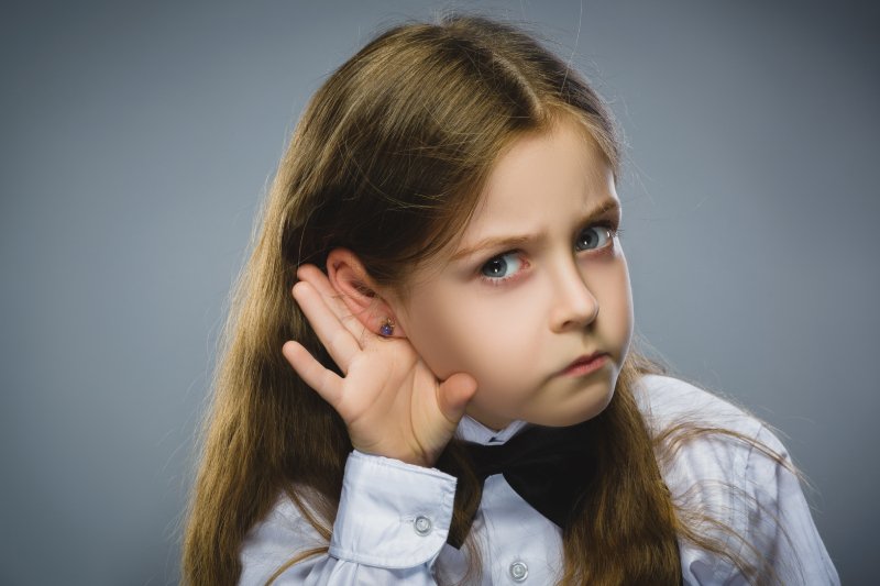 dziecko z ręką przy uchu